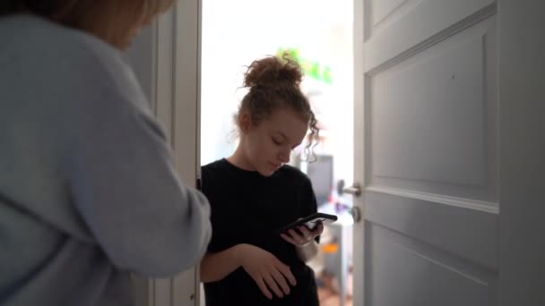 Conflict between mother and teenage daughter. The mother tries to talk to the girl. My daughter is distracted by her smartphone, Internet addiction. Teenager at her room — Wideo stockowe