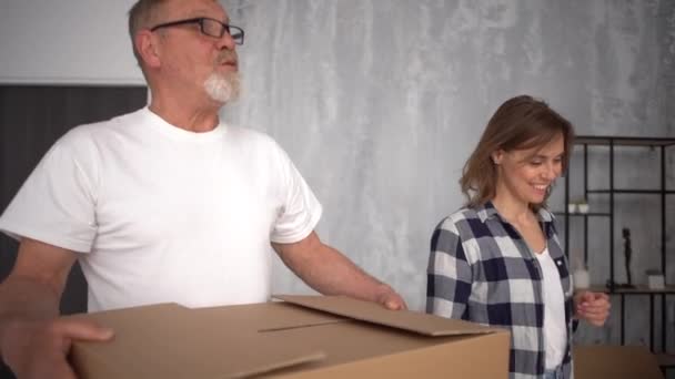 Mudarse a un nuevo apartamento de pareja madura enamorada. El marido y la mujer felices traen cajas de cartón a su nuevo apartamento. Concepto de bienes raíces y reubicación — Vídeo de stock