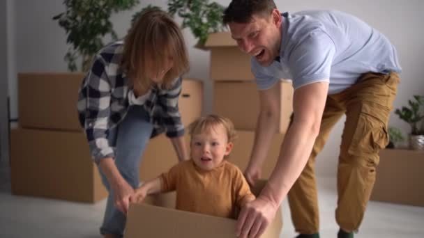 Retrato de marido y mujer jugando con su pequeño hijo en un nuevo hogar. Hipoteca, personas, vivienda y concepto de bienes raíces - familia feliz mudanza a casa nueva — Vídeo de stock