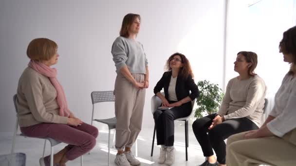 Mladá žena vstává a vypráví svůj příběh v kanceláři psychoterapeutů během skupinové terapie. Ostatní účastníci terapie tleskají — Stock video