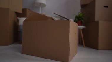 Sevimli küçük çocuk boş bir karton kutudan dışarı bakıyor. Yeni yürümeye başlayan çocuk, ailesi toplanıp taşınırken saklanıyor. Yeni konut ve emlak