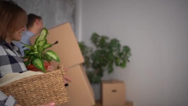 Jonge gelukkige paar knuffelen in een nieuw appartement tussen kartonnen dozen en dingen. Verhuizing en verandering van woonplaats — Stockvideo