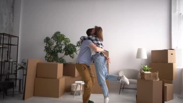 Novomanželé se nastěhovali do nového bytu a šťastně se objímali mezi kartonovými krabicemi. Koncept přemísťování a nemovitostí a pronájmu nemovitostí — Stock video