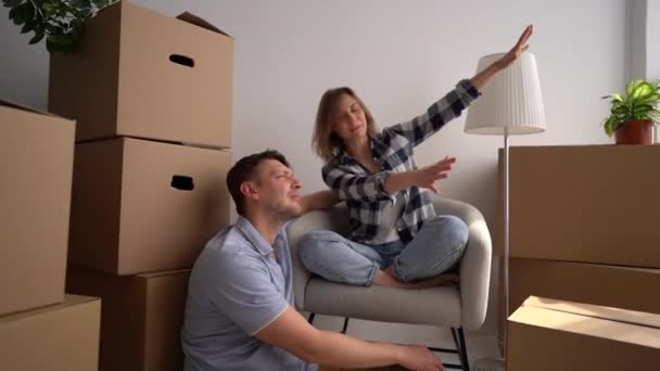 Divertidos recién casados en su nuevo apartamento están planeando desempacar las cajas. solo después de la reubicación a un nuevo hogar. Concepto inmobiliario — Vídeo de stock