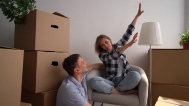 Heyecanlı kadın erkeğine yeni eve ne tür mobilyalar koyacaklarını söylüyor. Yeni bir daireye taşındıktan sonra mutlu genç çift.