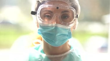 Koronavirüs enfeksiyonuyla mücadele sırasında koruyucu kıyafetli bir doktor. Koruyucu giysiler, gözlük ve maske takmış bitkin bir doktor. Coronavirüs salgını sırasında üniformalı bitkin bir doktor.