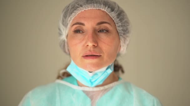 Устала грустная женщина-врач после тяжелого дня в отделении интенсивной терапии. Снимает маску и очки, на лице видны следы — стоковое видео
