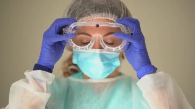 Güzel bir kadın doktor, işe başlamadan önce yüzüne koruyucu bir maske takar. Coronavirus covid-19