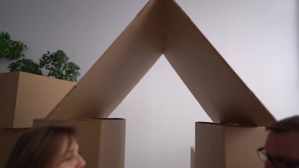 Stěhování do nového domu, realitního a hypotečního projektu. Manžel a manželka, šťastný manželský pár sedí na podlaze na pozadí lepenkových krabic — Stock video
