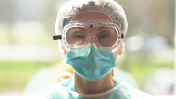 Beautiful female doctor in a protective suit during the fight against coronavirus infection. Exhausted doctor in protective clothing, glasses and mas during the coronavirus outbreak — Stock Video