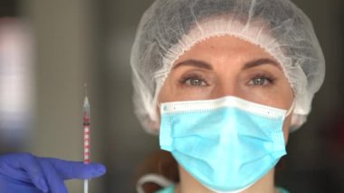 Tıbbi maske takan ve şırıngayı aşıyla dolduran Doktor veya Hemşire portresi. Aşılama Kavramı