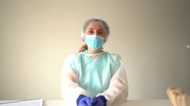 Deneyimli virolog Zhenshina covid-19 'un semptomları ve tedavisi hakkında konuşuyor. Maskeli ve koruyucu giysili kadın doktor hastaya tavsiyelerde bulunur.