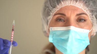 Tıbbi maske takan ve şırıngayı aşıyla dolduran Doktor veya Hemşire portresi. Aşılama Kavramı