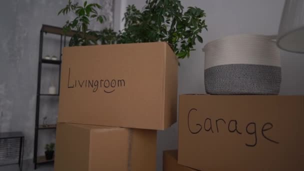 Cardboard boxes with inscriptions garage, kitchen, living room, bedroom, bathroom. Moving, relocation and minimalism concept — Stock Video