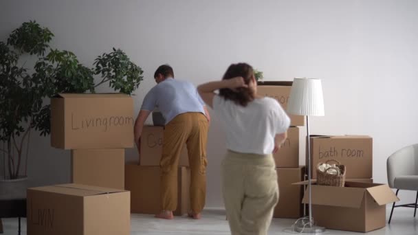 Getrouwd stel haalt de ingepakte spullen uit het appartement. Verhuizen naar een nieuw huis, minimalisme en decluttering concept — Stockvideo