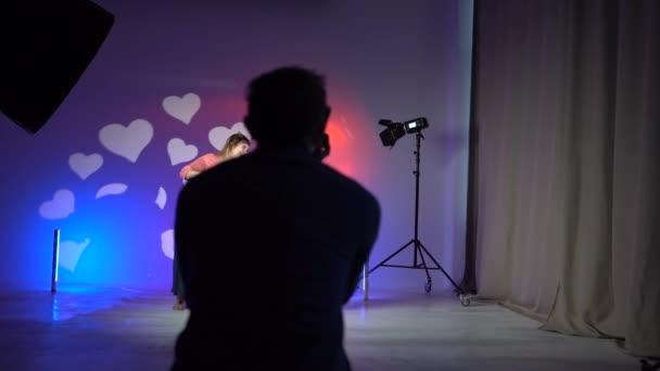 Неузнаваемый видеооператор снимает портрет двух девушек, танцующих в неоновом свете. Съемки рекламы, за кулисами студийных съемок — стоковое видео