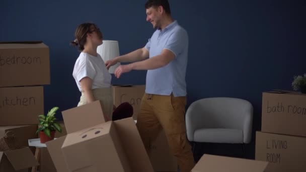 Man en vrouw zijn moe van het inpakken voor de verhuizing. De man omhelst de uitgeputte droevige vrouw en kust haar. Problemen met onroerend goed, rommel, consumptiemaatschappij — Stockvideo