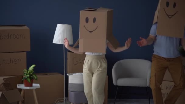 Pareja irreconocible, marido y mujer, bailando con cajas de cartón en la cabeza, vídeo divertido. Concepto de traslado y reubicación. Embalaje y decluttering — Vídeo de stock