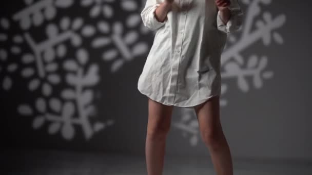 Retrato de estudio de una encantadora chica rizada descalza con una camisa blanca. La joven de pelo rizado está bailando disfrutando de la música. Concepto de belleza natural — Vídeos de Stock