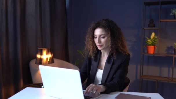 Skup się modna kobieta biznesu w garniturze pracuje na laptopie w przytulnym biurze. Pewna siebie, odnosząca sukcesy kobieta, szefowa, przedsiębiorczyni, rozmawiająca przez internet na komputerze w miejscu pracy. 4K — Wideo stockowe