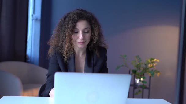 Μια επιχειρηματίας με μαύρο κοστούμι δουλεύει στο γραφείο με λάπτοπ. Η οικονομολόγος των κοριτσιών επικεντρώνεται στις εργασίες της κατά τη διάρκεια της εργάσιμης ημέρας. — Αρχείο Βίντεο