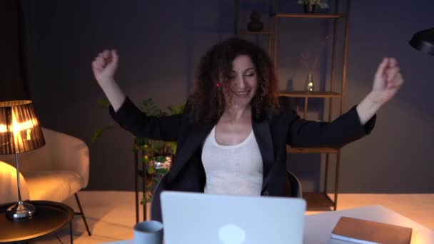 Die erwachsene Geschäftsfrau mit Kopfhörer hört im dunklen Büro Musik und arbeitet mit dem Laptop und genießt das Lieblingslied bei der Arbeit. Menschen, Entspannung und Arbeitsplatzkonzept — Stockvideo