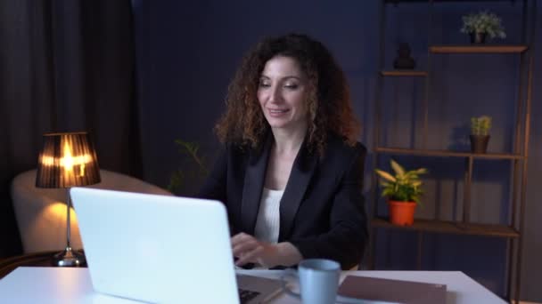 Empregada empregada sentada na mesa usando laptop trabalhando demais à noite com caneca de chá no escritório. 4K — Vídeo de Stock