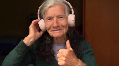 Çok yaşlı bir kadın, köy emeklisi, kablosuz kulaklıkla müzik dinliyor. Mutlu emeklilikler, insanlar ve aletler