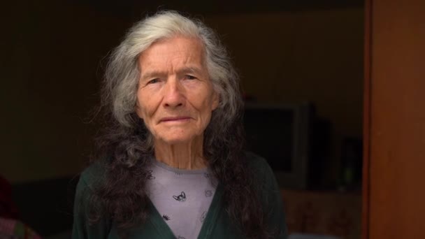 Портрет експресивної старої жінки на вулиці біля її будинку. Портрет сіро-волосистої старої леді з довгим волоссям. Дивлячись на камеру — стокове відео