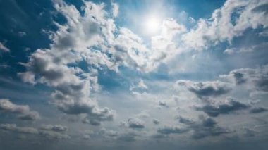 Beyaz kabarık bulutların güzel zamanlaması. Hafif mavi gökyüzünde hareket ediyor. Güneş bulutların arasından ışıl ışıl parlıyor..