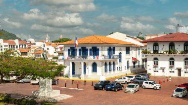 Panama Şehri, Panama. 12 Şubat 2024. Casco Viejo 'daki Plaza de Francia' daki tarihi Fransız Büyükelçiliği binası sömürge mimarisi ve parçalı bulutlu gökyüzünün altında park edilmiş arabalar..