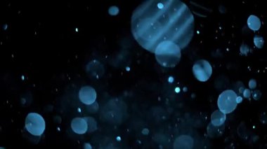 Hareket eden parçacıklar mavi Bokeh, siyah arkaplan üzerinde