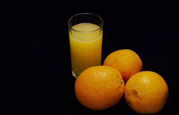 Három Narancs Egy Pohár Gyümölcslé Sötét Alapon — Stock Fotó
