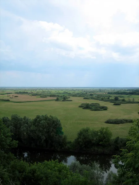 Nehrin ötesindeki yüksek kıyıdan su çayırlarına kadar panoramik manzara. Sonsuz tarlalar ve ormanlar ufuktaki sonsuz düz çizgiye kadar uzanıyor..