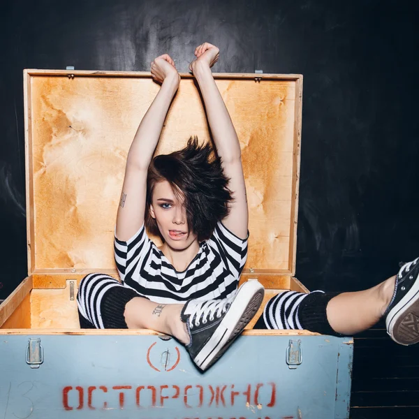 Menina vestindo pijama listrado em caixa de madeira — Fotografia de Stock