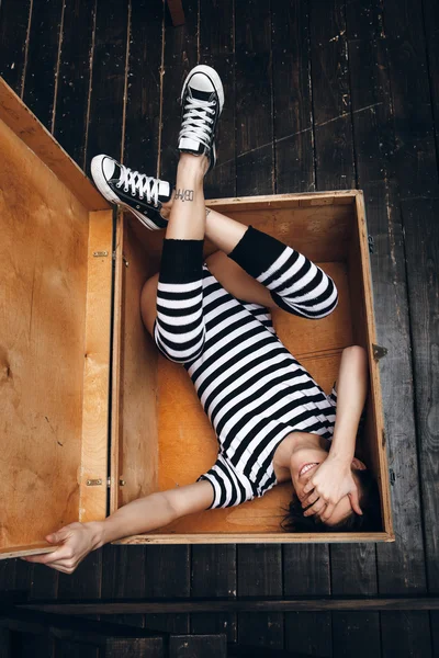 Chica en traje de cuerpo a rayas en caja de madera —  Fotos de Stock