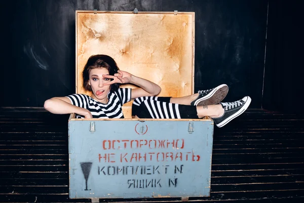 Girl wearing striped pajamas in wooden box — Stock Photo, Image