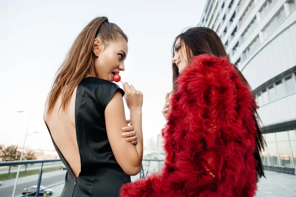 Dos jóvenes chicas de moda chupando piruletas — Foto de Stock
