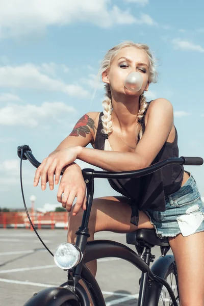 Pretty blonde woman with bicycle in city — Stock Photo, Image