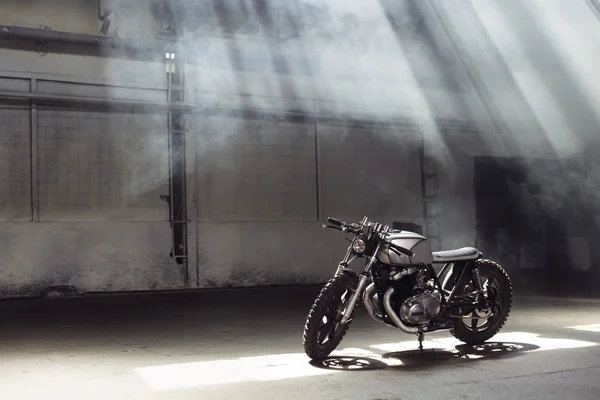 Motocykl, stojící v temné budově v slunečních paprscích — Stock fotografie