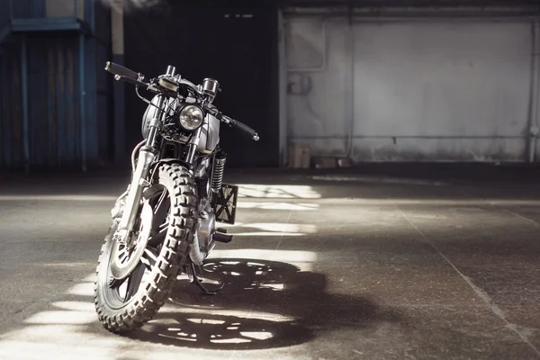 Moto debout dans le bâtiment sombre dans les rayons du soleil — Photo