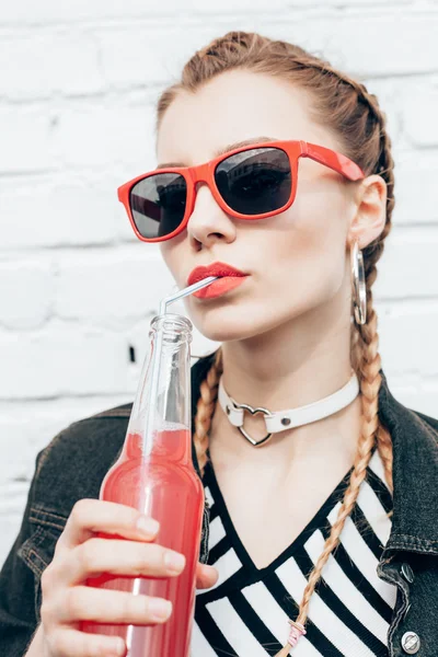 Молодая женщина пьет разноцветные коктейли из бутылок — стоковое фото