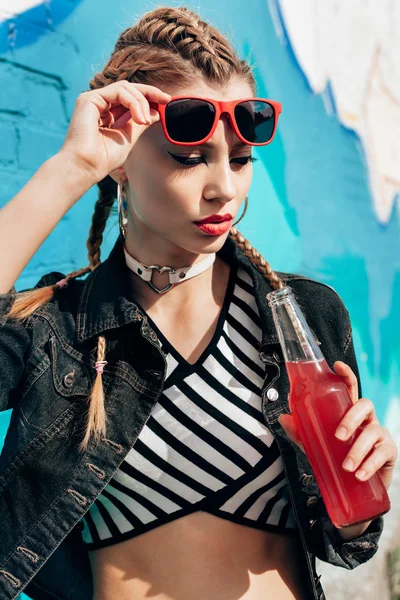 Молодая женщина пьет разноцветные коктейли из бутылок — стоковое фото