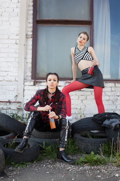 Two young girls sitting on tires on sunny day — Stock Photo, Image