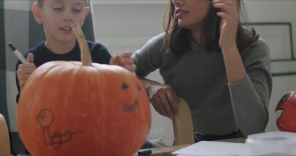 Mujer con hijo pintar calabaza para Halloween — Vídeo de stock