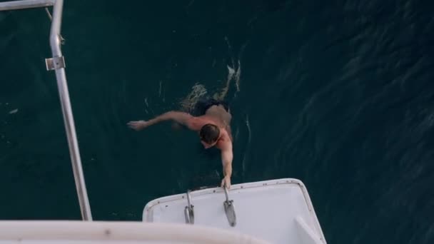 Joven saltando desde el acantilado en el océano de agua azul — Vídeo de stock