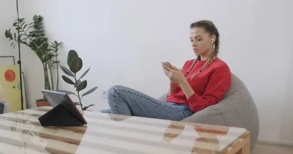 Chica sentada en casa y hablando por teléfono —  Fotos de Stock