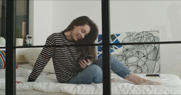 Meisje liggend op bed en het houden van telefoon — Stockvideo