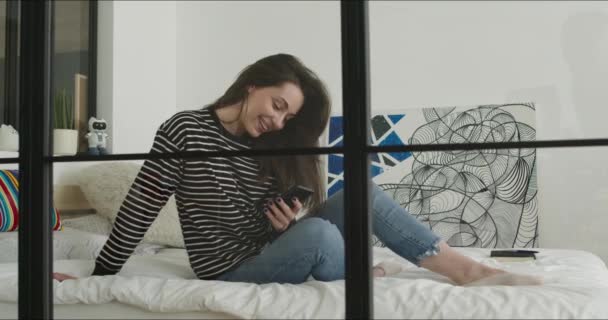 Gadis berbaring di tempat tidur dan memegang telepon — Stok Video