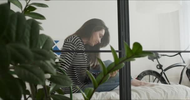 Girl lying on bed and holding phone — Stock Video